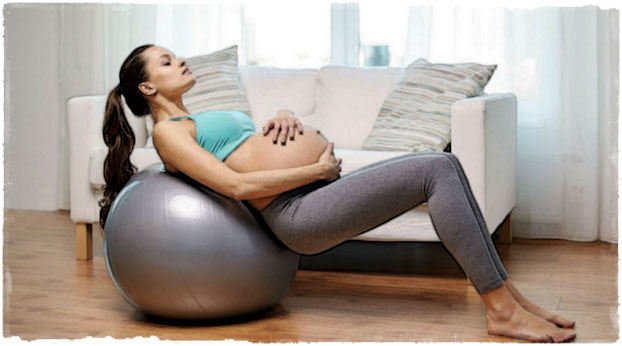 Беременная девушка лежит на фитболе